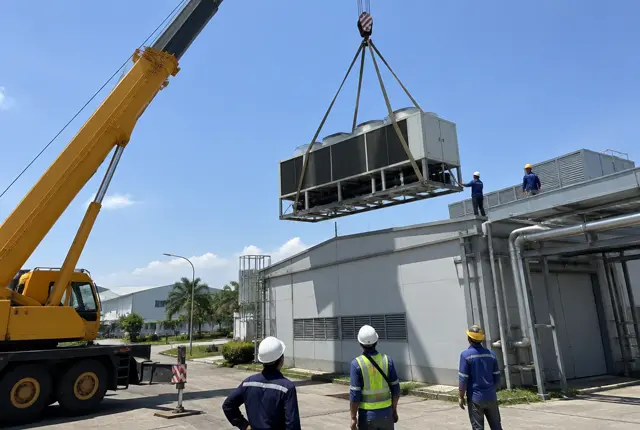 Crane mengangkat unit chiller air cooled ke atap pabrik di Karawang